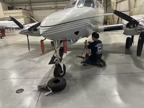 Hangar13 technician servicing the nose landing gear of a twin-engine aircraft